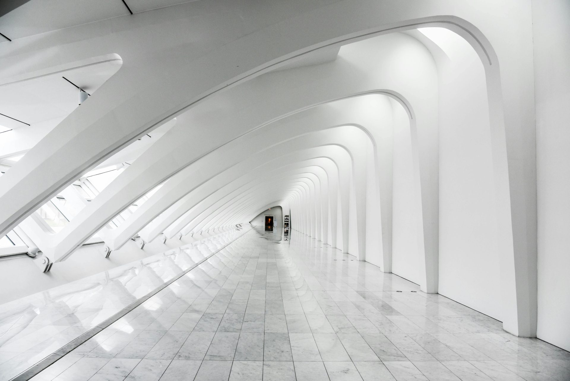 Pasillo arquitectónico blanco con arcos curvos iluminado por luz natural