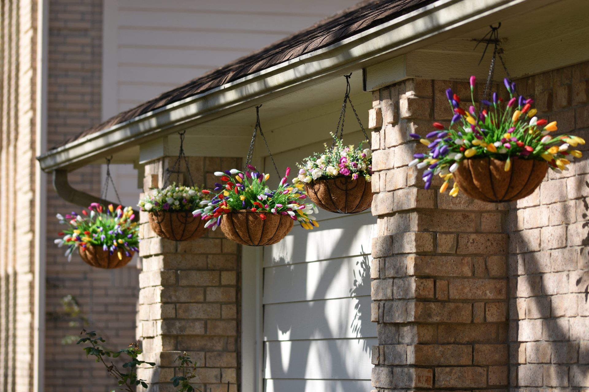 Fachada de ladrillo con maceteros colgantes llenos de flores de colores
