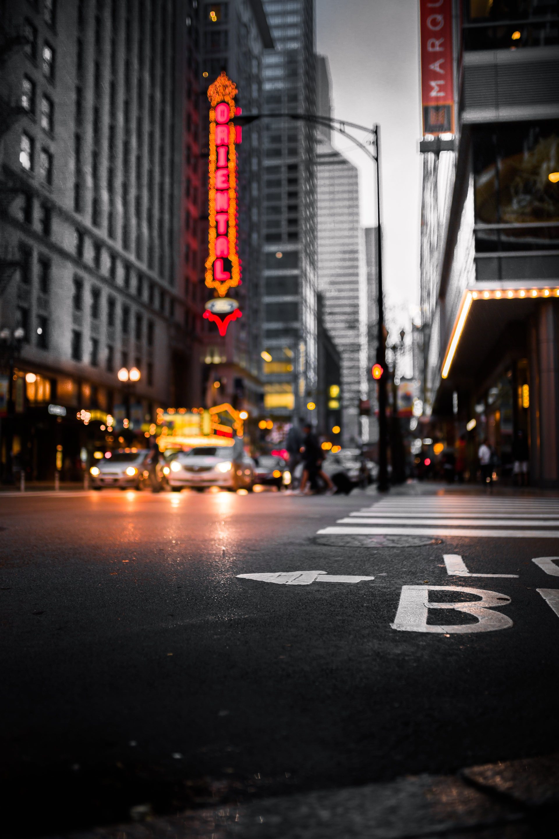 Calle de una ciudad al atardecer con luces de neón y coches en movimiento