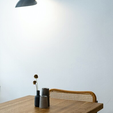Mesa de madera con una lámpara de pared negra y sillas de rejilla