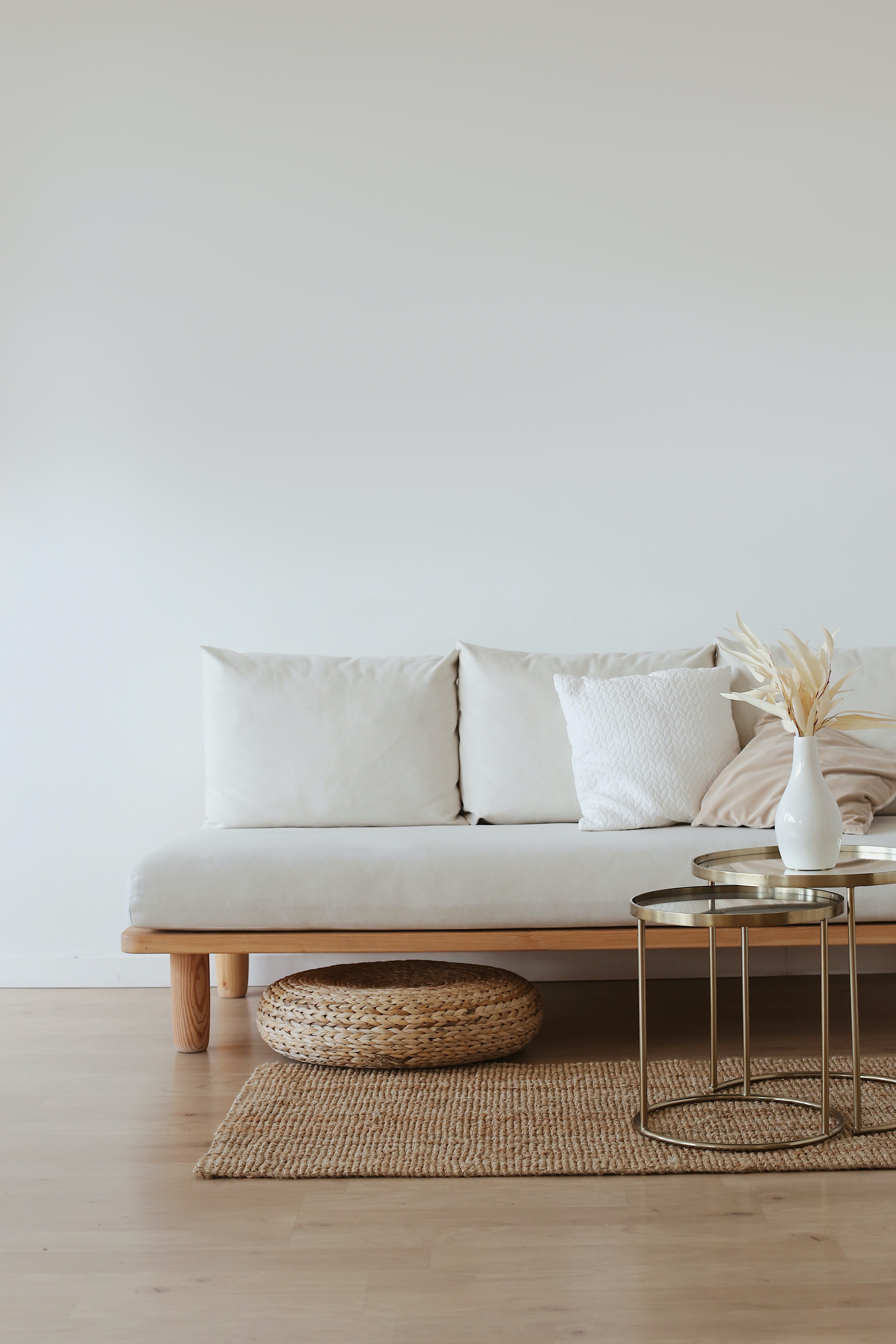 Salón minimalista con un sofá blanco, cojines claros y una mesa auxiliar redonda